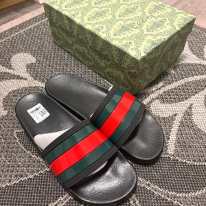 Gucci sandaler med röd och grön rand - Gucci sandaler i svart med breda remmar i klassiska röd-gröna ränder. Snygg och stilren design med platt sula och rund tå. Tillverkade i syntetmaterial med präglad logga under sulan. Perfekta för sommaren och chill dagar.