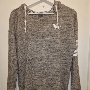 Grå hoodie från Victoria's Secret  - Säljer en grå hoodie från Victoria's Secret PINK  collection med stoor huva. Den har en skön loose passform/ är oversize. Man kan även vika upp den under sportbhn för en cool look. 