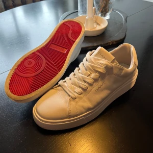 Vita sneakers från GANT med röd sula - GANT sneakers, vita läderskor, använda typ två gånger. Storlek 42. Röd detaljsula. Nypris ca 1200