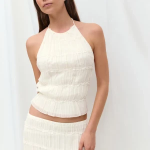 Vit omlott halterneck topp med snörning - Säljer en ljusvit halterneck topp med omlott och snörning i ryggen. Toppen är croppad och har en plisserad struktur med tunna band som knyts både i nacken och ryggen.