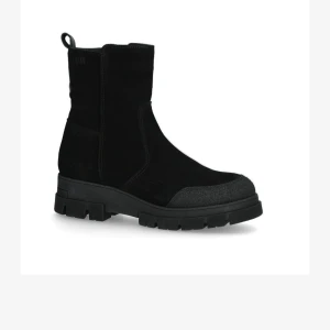 Svarta boots från Dasia i mocka med grov sula - Snygga svarta boots från märket Dasia i mocka med grov platt sula och rund tå. Stöveln har en enkel design med förstärkt tåparti och en praktisk ögla baktill. Perfekt för dig som gillar stilrena och robusta skor med lite edge.