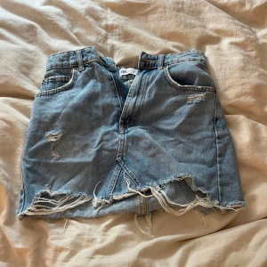 Blå jeanskjol med slitningar från Zara - Säljer en jätte fin blå jeans kjol från Zara i storlek xs. Bra skick och säljer för den inte passar🥰