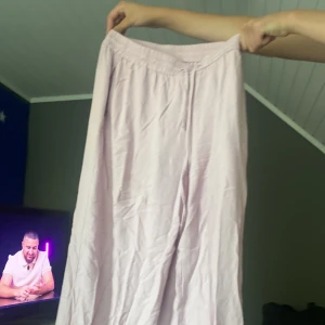 Ljusrosa linnebyxor med wide fit - Säljer ett par ljusrosa linnebyxor med skön, vid passform och elastisk midja. Byxorna har raka ben och är perfekta för chill dagar eller när du vill ha en soft och luftig stil. Materialet är linne och färgen är riktigt fräsch ljusrosa.
