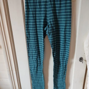 Pyjamas byxor - Ett par blå och grön randiga pyjamas byxor från polarn och pyret.