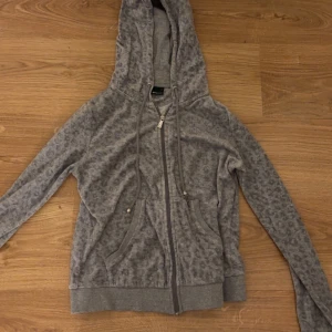 Grå leopardmönstrad hoodie - Säljer en grå hoodie med leopardmönster. Tröjan har dragkedja framtill, två fickor och justerbar huva med snören. Endast använd 5 gånger då den inte riktigt är min stil längre. Den är i storlek m men skulle absolut inte säga att de stämmer den sitter mer som en xs. Den har inga hål eller fläckar. 