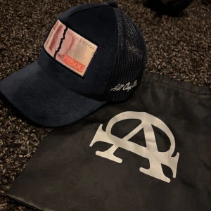 Bruce Lee, All Cap One limited edition keps - En unik marin blå Bruce lee X All Cap one collab limited edition keps med riven 500 sedel på framsidan som jag har haft länge men bara använt några få gånger.   går inte att köpa längre såldes bara 500 st kepsar man får med original All Cap One pås 