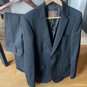 Svart kostym - lords & fools  - Klassisk svart kostym från Lords & fools med kavaj och matchande byxor. Kavajen har två knappar framtill, smala slag och fickor med lock. Perfekt nu inför bal eller student! Endast använd vid två tillfällen. Nypris ca 6000, säljs för 1200 eller bud 