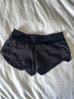 Lululemon speed up shorts - Använda med viss nyansskillnad i tyget och loggan har delvis lossnat (se detaljbild) men verklig färg är inte så ljust som på närbilderna. Etiketten utklippt pga skav. 