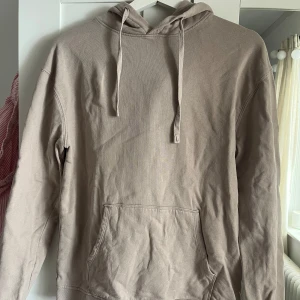 Beige hoodie med ficka framtill - Säljer en enkel grå/beige hoodie med huva och ficka framtill. Tröjan har långa ärmar och snörning i huvan. Perfekt för en avslappnad stil. Skriv för fler bilder💞
