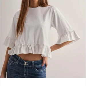 Vit blus med volang - Säljer en söt vit blus från nelly med volangdetaljer vid ärmens slut och längst ner på tröjan.💞💞