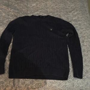 Mörkblå stickad tröja från GANT - Klassisk mörkblå stickad tröja från GANT med diskret logga på bröstet. Tröjan har rund halsringning och långa ärmar, samt ribbade muddar vid ärmslut och nederkant. Kan gå ner i pris!