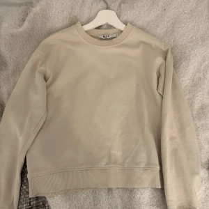 Beige sweatshirt med rund hals - Säljer en stilren beige sweatshirt med rund halsringning och ribbade muddar vid ärmslut och nederkant. Perfekt för en avslappnad och enkel look. Passar till det mesta och är superbekväm.