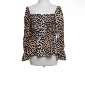 Leopardmönstrad blus från H&M - Trendig blus från H&M med leopardmönster och smockad överdel. Blusen har långa ärmar med volang vid ärmslut och en fyrkantig ringning. Perfekt för dig som vill sticka ut med ett djurmönster! Liten i storleken 