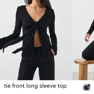 Svart långärmad topp med rosett - Svart långärmad topp med djup v-ringning och en stor rosett framtill. Snygg och enkel design som passar till många olika outfits.