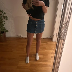 Jeanskjol - Jeanskjol med knappar framtill. Går att använda med nervikt kant om man vill ha den kortare eller annars klippa den då den redan har ”klippt” kant. ”riktiga” längden syns på sista bilden. som nyskick
