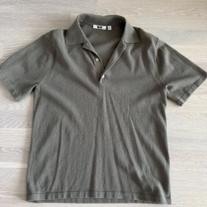 Olivgrön pikétröja från Uniqlo - Säljer en stilren olivgrön pikétröja från Uniqlo med klassisk krage och knappar framtill. Tröjan har korta ärmar och är tillverkad i mjukt material som passar perfekt till vardags. Enkel och tidlös design. Storlek xs (passar S)