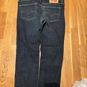 Levi's 511 mörkblå jeans - Säljer ett par mörkblå Levi's 511 jeans med klassisk femficksdesign och snygga kontrastsömmar. Modellen är slim och passar perfekt till vardags. Midjemått W32 och längd L32.
