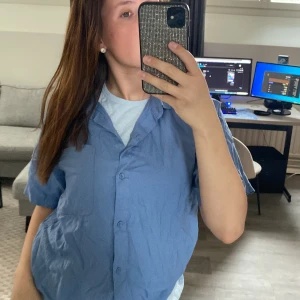 Blå kortärmad skjorta - Säljer en blå kortärmad skjorta med knappar framtill. 