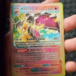 Pokémonkort Mawile VSTAR 260 HP - Säljer ett Pokémonkort med Mawile VSTAR, 260 HP. Kortet har färgglad framsida med holografiska detaljer och text på engelska. Baksidan har klassisk Pokémon-design med Pokéboll och logotyp. Perfekt för samlare eller Pokémon-fans.