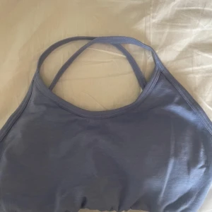 Ljuslila croppad träningstopp - Säljer en ljuslila croppad linnetopp från Relode med smala korsade axelband i ryggen. Perfekt för träning. Mjukt och stretchigt material.