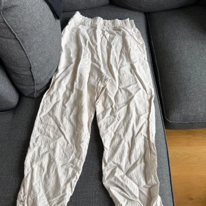 Beiga linnebyxor från H&M - Säljer ett par beiga linnebyxor från H&M med resår i midjan. Byxorna har en avslappnad passform och är perfekta för varmare dagar. Lätta och luftiga med rak siluett och diskret struktur i tyget. Kommer styrkas om kunden vill innan försäljning. Uppsträtta under för att öka längden lite 