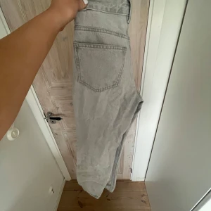 Ljusgrå jeansbyxor med raka ben - Säljer ett par ljusgrå jeansbyxor med klassisk femficksdesign och raka ben. Byxorna har normal passform och medelhög midja, perfekta för en avslappnad stil. Snygga att matcha med både t-shirt och stickad tröja.