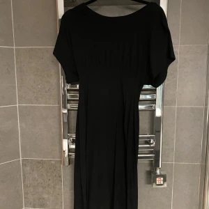 Svart långklänning med dragkedja i ryggen - En svart mamma långklänning med rund halsringning och korta ärmar. Klänningen har en markerad midja och en synlig dragkedja i ryggen. Perfekt för en stilren och enkel look. Har använts som vanlig klänning( dvs inte mammahjärtat Ming eftersom den är snyggt följsam även om man inte är gravid). Stl S