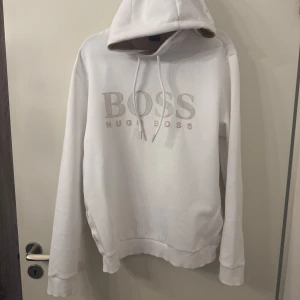 Vit hoodie från Hugo Boss - Säljer en stilren vit hoodie från Hugo Boss, knappt användt, inga hål eller fläckar