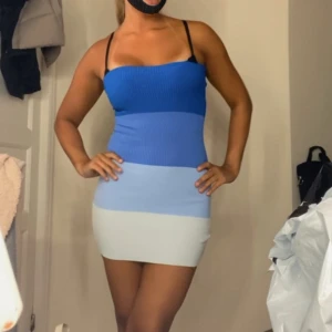 Randig tight klänning med smala axelband - Säljer en tight, kort klänning med smala axelband och horisontella blockränder. Finns i både blå och rosa nyanser. Klänningen är ribbad och har en kroppsnära passform, perfekt för dig som vill sticka ut.