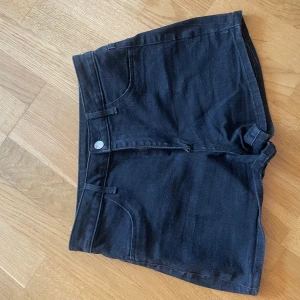 Svarta jeansshorts från H&M - Svarta jeansshorts från H&M med klassisk femficksdesign och knapp- samt dragkedjestängning. Modellen är kort och har hög midja, perfekt för varma dagar. Snygga att matcha med en enkel topp eller hoodie. Mycket bra skick!🖤