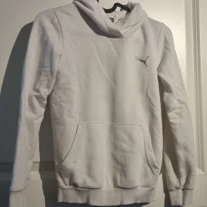 Vit hoodie från Puma 8-10 år (140) - Säljer en vit hoodie från Puma med logotryck på ärmen och liten Puma-logga på bröstet. Tröjan har huva, lång ärm och en magficka framtill. 