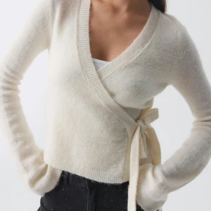 Vit omlottkofta från GinaTricot - Mysig vit omlottkofta från Gina med knyt i sidan. Tröjan är stickad och har långa ärmar samt en djup v-ringning. Perfekt för lager-på-lager och passar till allt!