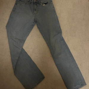 Blå jeansbyxor - Regular fit. Klassiska blå jeansbyxor med en rak passform. De har en traditionell femficksdesign och stängs med dragkedja och knapp. Perfekta för en avslappnad stil. 