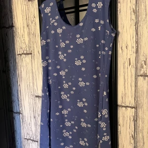 Blå blommig klänning - Säljer en söt blå klänning med vita blommor. Klänningen är ärmlös och har en bekväm passform. Perfekt för varma dagar och ger en fräsch look. 🌸