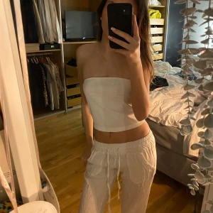 Vit ribbad tubtopp - Säljer en stilren vit ribbad tubtopp. Perfekt för varma sommardagar eller som en del av en lager-på-lager-look. Toppen är axelbandslös och har en tight passform som framhäver figuren. Passar till både jeans och kjol för en avslappnad eller uppklädd stil.