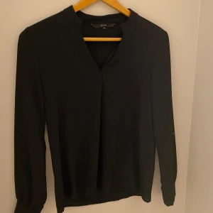 Svart blus från Vero Moda - Säljer denna snygga svarta blusen från Vero Moda. Blusen har en mindre v-ringning och är luftig. Perfekt till vardags eller lite finare tillfällen