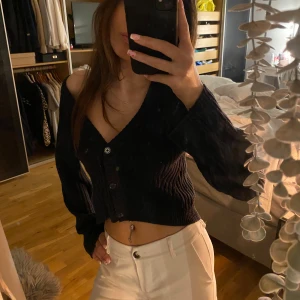 marinblå croppad kofta från H&M - Säljer en marinblå croppad kofta från H&M med knappar framtill. Den har långa ärmar och en ribbad struktur som ger en stilren look. Perfekt för att lägga till en extra touch till din outfit.