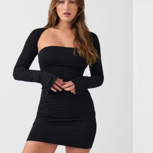 Svart tight klänning - Snygg svart tight klänning med långärmad design och axelbandslös stil. Perfekt för en kväll ute med vänner. Klänningen har en kort längd och är tillverkad i ett stretchigt material för en bekväm passform. Använd få gånger.