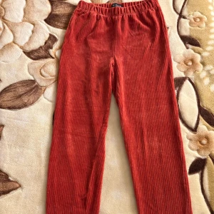 Röda byxor från XOXO Friends, stl 170 - Mycket fint skick - XOXO Friends. Rödaktig färg. Högmidjade. Ribbade. Mjukt material. Figurnära. Fickor på vardera sida. Band vid ankeln. Stretch. Storlek: 170. Material: 70% bomull, 27% polyester, 3% elastan. Maskintvätt i 40 grader. Skick: Mycket fint. Nypris: 199 kr.