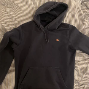 Mörkblå hoodie från Dickies - Säljer en mörkblå hoodie från Dickies. Den har en klassisk design med en stor ficka framtill och justerbar huva. Perfekt för en avslappnad stil. VÄLDIGT skön och bra skick 