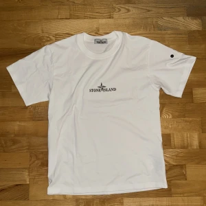 Vit t-shirt från Stone Island - Säljer min brors feta vita t-shirt från Stone Island med deras ikoniska logga tryckt på bröstet och en stor design på ryggen. Tröjan är använd ett fåtal gånger pga att den var för liten på han. Perfekt för att hålla stilen under sommaren. Tveka inte med att höra av dig om du har frågor. OBS! Tyvärr följer inte stone island patchen med därav priset❗️Kom gärna med prisförslag!