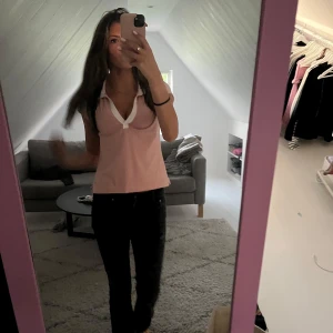 Rosa topp med vit kant - Säljer en söt rosa topp med vit kant runt den djupa v-ringningen. Toppen har en tight passform och är ärmlös, perfekt för varmare dagar.