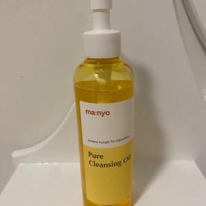 Pure Cleansing Oil från ma:nyo - Säljer en Pure Cleansing Oil från ma:nyo. Denna rengöringsolja kommer i en praktisk pumpflaska och är perfekt för att ta bort smink och orenheter. Oljan har en gyllene färg och är känd för sina vårdande egenskaper.