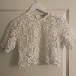 Vit spetsblus från Amisu - Säljer en kort söt vit spetsblus från Amisu i storlek XS. Blusen är kortärmad och har en fin spetsdesign som ger en romantisk känsla. Blusen är perfekt att ha ett linne under för en fin ”layer-effekt”. Perfekt för att piffa upp vilken outfit som helst! 💫