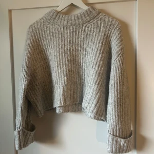 Grå stickad tröja från Gina Tricot - Säljer en mysig grå stickad tröja från Gina Tricot. Tröjan är croppad med långa ärmar och har en ribbad design. Perfekt för kyliga dagar. Hör av dig vid intresse! 😊