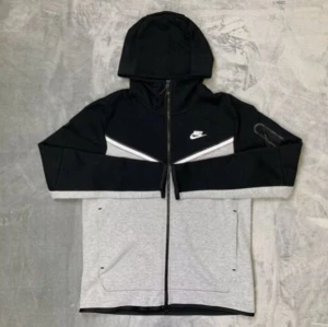 Gamla nike tech svart och grå - Snygg svart och grå hoodie från Nike med dragkedja och huva. Perfekt för en sportig look. Den har långa ärmar och en stilren design med Nike-logga på bröstet.
