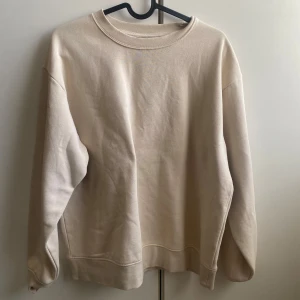 Beige sweatshirt - Säljer en stilren beige sweatshirt med rund halsringning. Tröjan har långa ärmar.  Tillverkad i ett mjukt material för extra komfort.