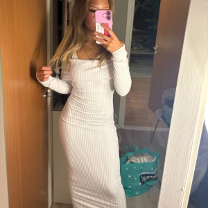 Vit ribbad långklänning - Säljer en stilren vit ribbad långklänning med offshoulder-design. Klänningen har en tight passform som framhäver figuren och långa ärmar för en elegant look. Perfekt för en kväll ute eller en speciell tillställning.