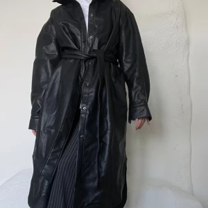 Skinnkappa Weekday - Snygg svart skinnkappa från Weekday med ett knytning framtill! 