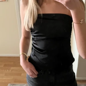 Svart siden tubtopp - Så snygg topp från Zara. Den är lite rynkad på kanterna vilket ger en snygg detalj. Passar perfekt till festliga tillfällen. Helt oanvänd med lappen på. Storlek xs. Skriva ifall fler frågor/ bilder💞💞